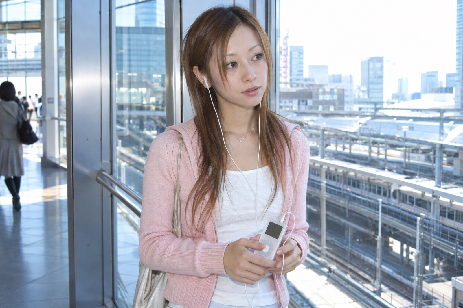 駅で携帯デジタル音楽プレーヤーを使う2001年の女性