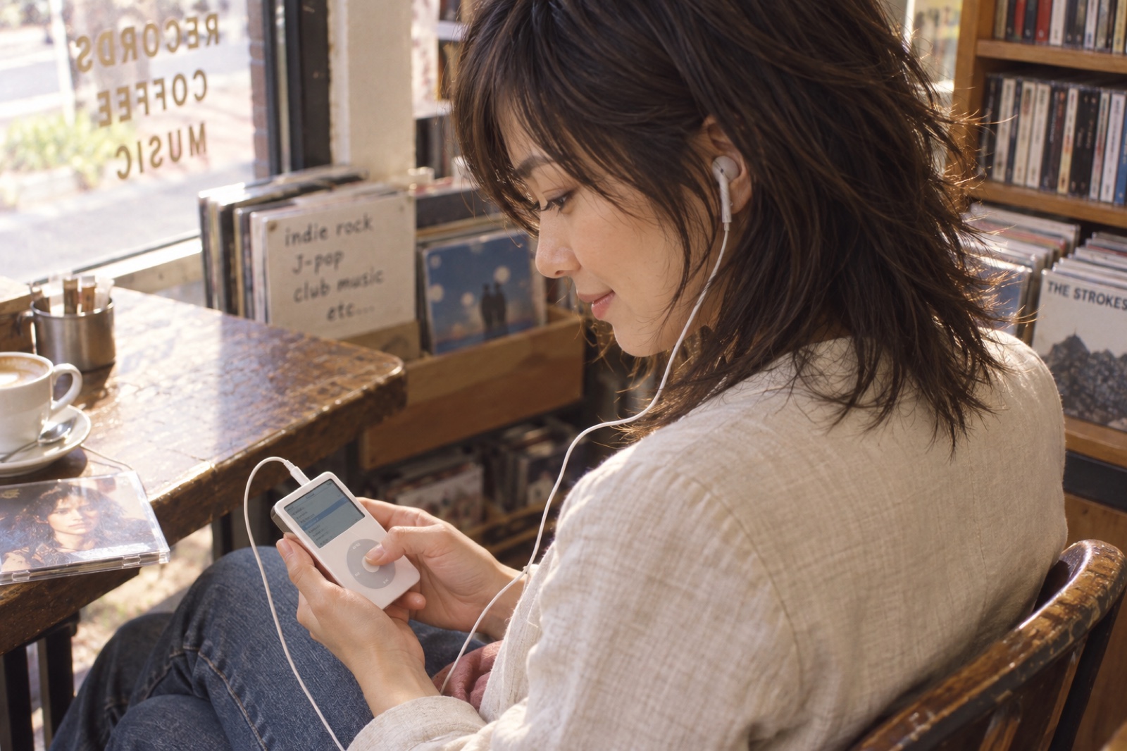 白いiPodで曲を選びながら音楽を楽しむ2005年の女性