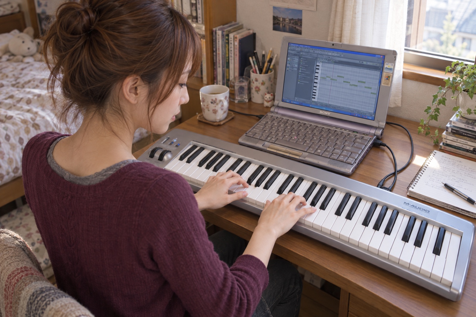 パソコンとMIDIキーボードを使い自宅で音楽を制作する2007年の女性