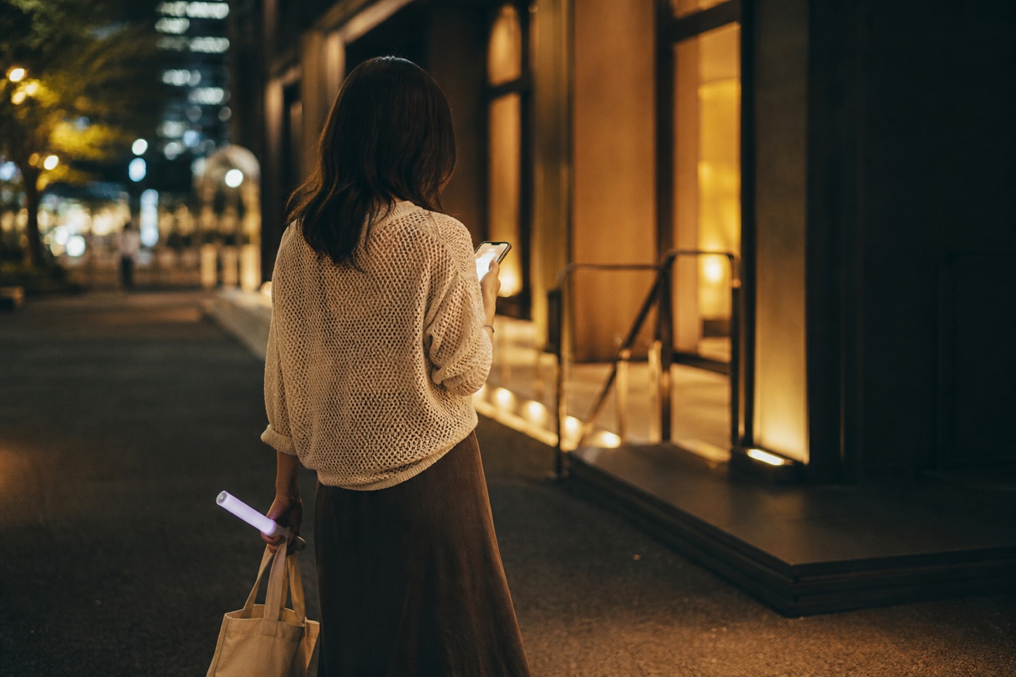 終演後の夜、会場の灯りを背にスマホでセトリを振り返りながら帰る様子